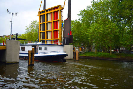 Amsterdam / Netherlands - July 11, 2019: Opening bridge to let boat pass underneath in a narrow...
