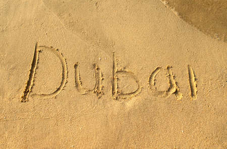 Dubai word on beach sand. Dubai city letters is written on a sand. Handwritingの写真素材