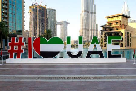 Dubai / UAE - December 3, 2019: Many UAE national flags with Dubai skyscrapers and Burj Khalifa on background. I love UAE words and sign. UAE National day. Flag day.のeditorial素材
