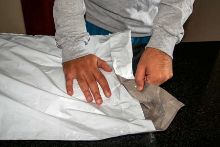 Man opening plastic parcel delivery. Online delivery plastic package. Postal serviceの写真素材