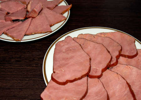 Smoked horse and beef meat slices on white plates on dark wooden background. Mixing meat delicacy,...