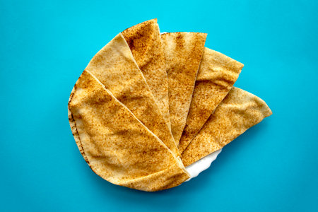 Famous traditional Arabic pita bread in white plate on blue background. Flat lay, top view.の写真素材