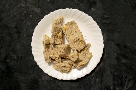 Sunflower seed halva in white plate on gray rustic background. Famous russian sweets. Halvah with...