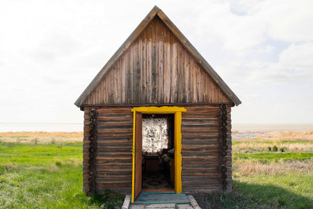 Old weathered wooden summer house in open field in summer timeの写真素材