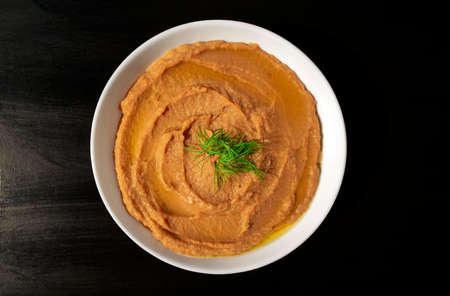 Famous traditional Arabic cuisine - peeled fava beans mashed plain in a white bowl on dark brown background. Top view. Foul Mudammasの写真素材