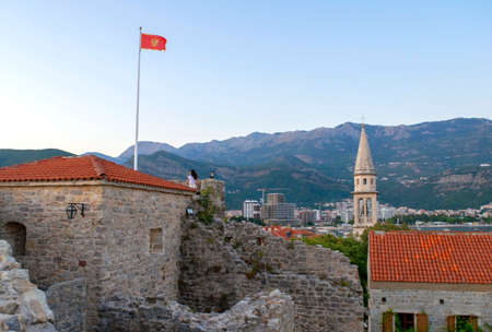 Montenegro - Budva: September 8, 2021: Montenegro flag on the Budva city and mountains background. Flag of Montenegro is flying over the old townのeditorial素材