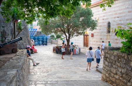 Montenegro - Budva: September 8, 2021: Old town of Budva with souvenirs next to Church of Holy Trinity. Heritage site with ancient buildings and green areaのeditorial素材