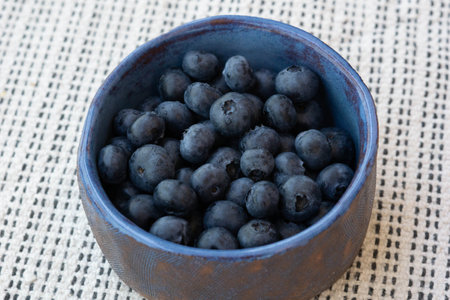 Breakfast mood. Fresh farm ripe blueberries berries in a blue ceramic crafts cup on a light background. Copy space. Vegan snackの写真素材