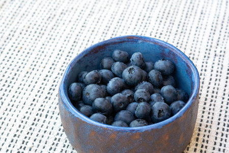 Close-up of fresh farm ripe blueberries in a blue ceramic vintage cup on a light background. Copy space. Vegetarian breakfastの写真素材