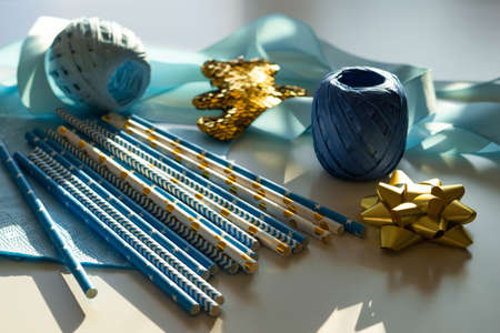 Baby showers decor. Blue and golden color straws, teddy bear, napkins, ribbons for gender reveal party, newborn baby, boys birthday.の写真素材