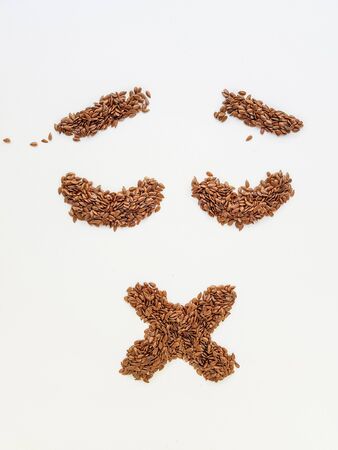 Flax seeds laid out in the form of emotions due to diet on a white background.の写真素材