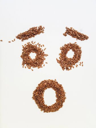 Flax seeds laid out in the form of emotions due to diet on a white background.の写真素材