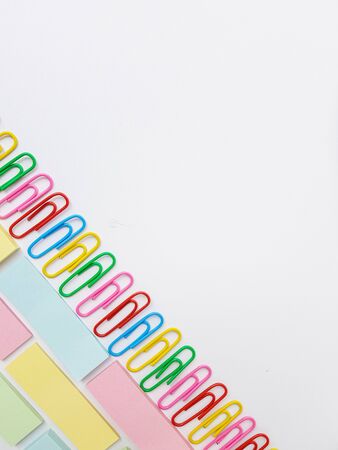 Multicolored blue, red yellow, pink, green, white metal paper clips on a white background.の写真素材