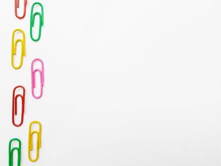 Multicolored blue, red yellow, pink, green, white metal paper clips on a white background.の写真素材