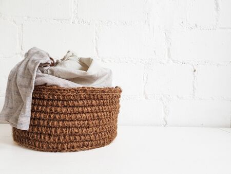 A wicker brown Laundry basket with dirty Laundry on the background of a gray sofa. Air conditioning and a plastic Cup of powder. High quality photoの写真素材