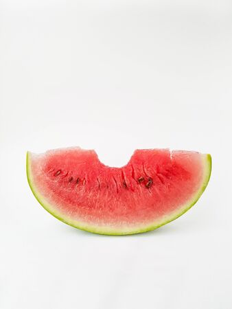 Juicy bright part of a red watermelon on a white background. A bit of watermelon. The trail from the teeth. High quality photoの写真素材