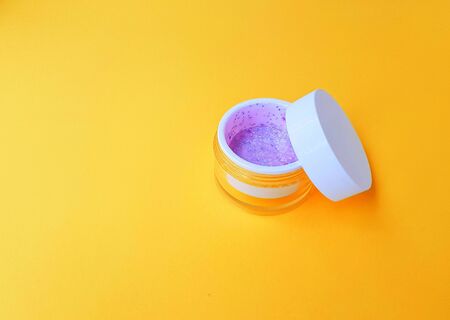 Transparent jar with cream and white lid on a bright yellow background. Space for text. High quality photoの写真素材