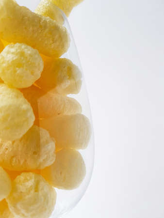 Yellow corn sticks in a transparent glass on a white background. High quality photo