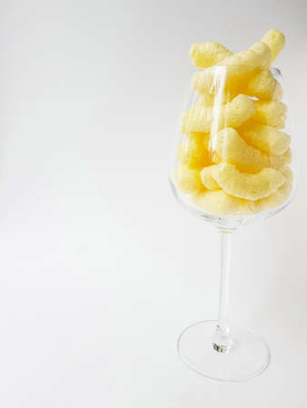 Yellow corn sticks in a transparent glass on a white background. High quality photo