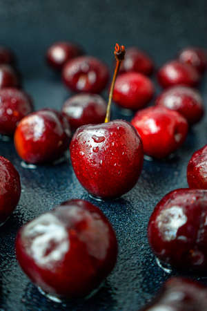 Bright ripe black cherry on a black background. Drops of water on the cherry. High quality photo