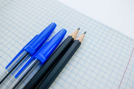 Ballpoint pen and pencils on a white blank sheet of paper in a cage. High quality photoの写真素材