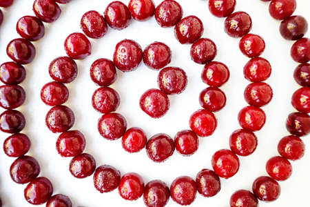 Red cherry ripe juicy is laid out in a spiral on a white background. High quality photo