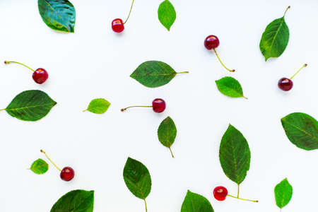 Bright red juicy ripe cherry with green leaves scattered on a white background. High quality photoの写真素材