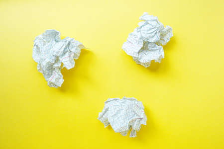 A crumpled sheet of white paper in a notebook cage on a bright yellow background. . High quality photoの写真素材