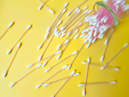 Cotton sticks pink plastic on a yellow background. Personal hygiene and health. Cosmetology and medicine. High quality photoの写真素材