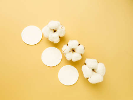 Cotton cotton discs on a yellow background. Personal hygiene and care. Medicine and cosmetology. High quality photoの写真素材