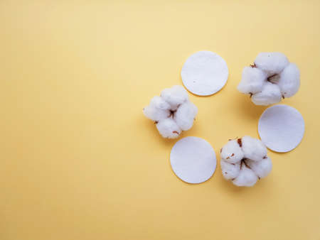 Cotton cotton discs on a yellow background. Personal hygiene and care. Medicine and cosmetology. High quality photoの写真素材