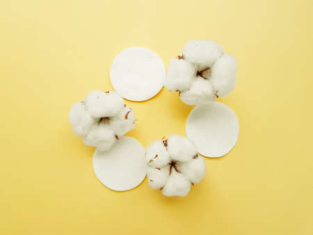 Cotton cotton discs on a yellow background. Personal hygiene and care. Medicine and cosmetology. High quality photoの写真素材