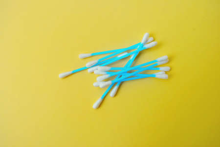 Ear cotton buds are blue on a yellow background. Cosmetology and medicine. Personal hygiene and care. High quality photoの写真素材