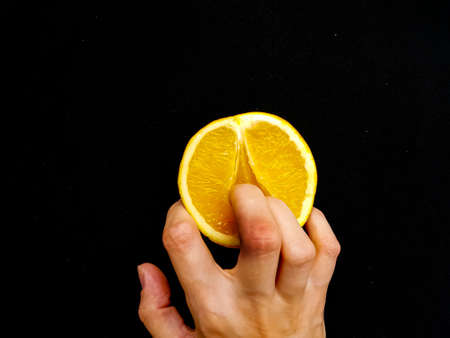 Sex concept. A vagina symbol. Fingers on an orange on a black background. High quality photoの写真素材