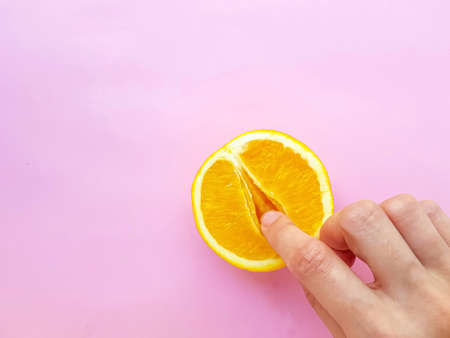 A vagina symbol. The concept of sex. Finger on an orange on a pink background. High quality photoの写真素材