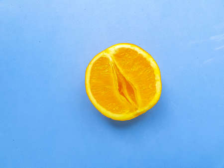 Bright juicy orange on a blue background. A vagina symbol. The concept of sex. Womens personal...