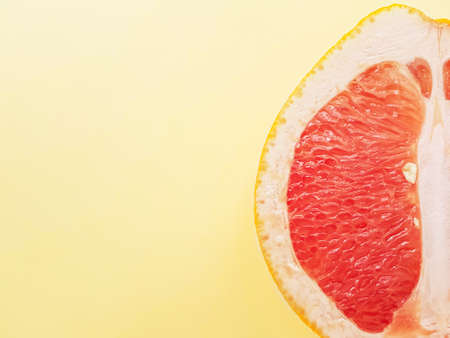 Red ripe juicy grapefruit in a cut on a yellow background view from above. The concept of diet and healthy eating. A place for text. . High quality photoの写真素材
