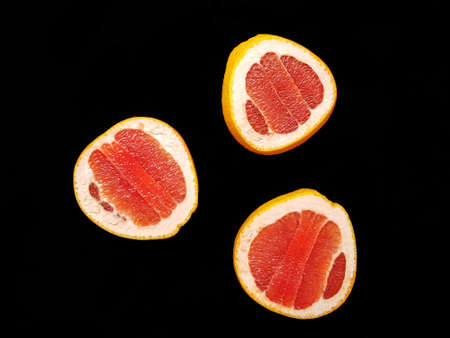 Red ripe juicy grapefruit in a cut on a black background view from above. The concept of diet and healthy eating. A place for text. . High quality photoの写真素材
