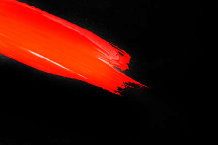 A smear of red paint on a black background. A place for text. . High quality photoの写真素材