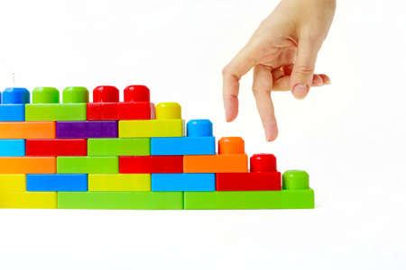 Step by step to the top. Business concept of successful financial growth. The womans hand steps on the steps of a childrens multi-colored designer on a white background. High quality photoの写真素材