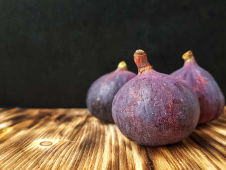 Bright ripe figs on the wooden surface at the back of a dark background. High quality photoの写真素材