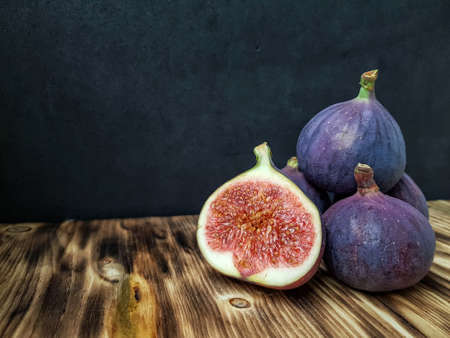 Bright ripe figs on the wooden surface at the back of a dark background. High quality photo