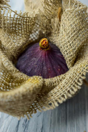 Bright purple luscious figs wrap in fabric on a gray wooden background. . High quality photo