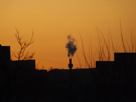 Pipe with black smoke against the background of the orange sky during sunset.の写真素材