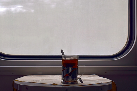A glass of tea on a table in the train car.