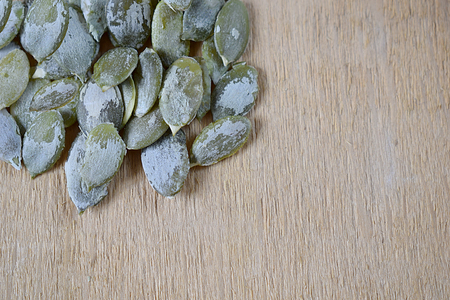 Peeled pumpkin seeds in an orderly manner on a wooden background.の写真素材