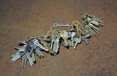 Many old keys in bundles on a rusty sheet of iron.