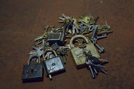 Many old keys in bundles and locks on a rusty sheet of iron.