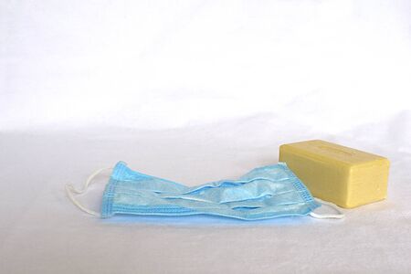 Bar of soap and a medical mask on a white background, concept of preventing the epidemic of viral diseases.の写真素材