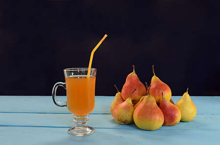 Pear juice in a glass and pears on a blue wooden table.の写真素材